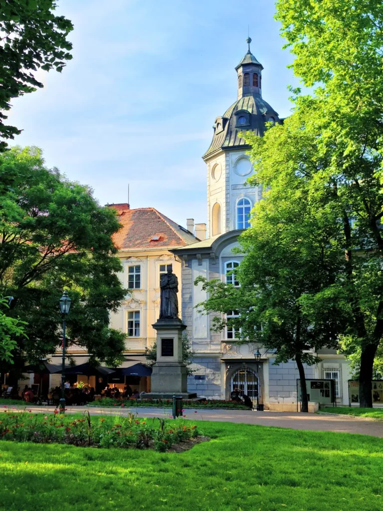 Літній парк у Плзні з пам’ятником, квітниками та історичною будівлею